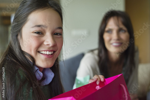 Photo: Girl holding a shopping bag and smiling with her mother Girl holding a shopping bag and smiling with her mother