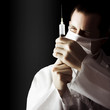 Photo: Male doctor with needle syringe on dark background Male doctor with needle syringe on dark background