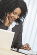 Foto: African American Woman Using Cell Phone & Laptop in Office African American Woman Using Cell Phone & Laptop in Office