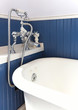 White tub with antique hardware and blue wood wall.
