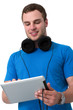Foto: Young man with headphones working on a tablet pc Young man with headphones working on a tablet pc