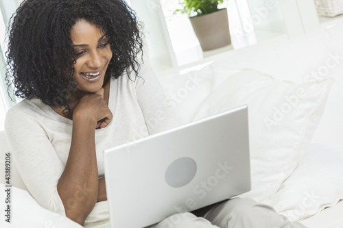 Photo: African American Woman Using Laptop Computer At Home on Sofa African American Woman Using Laptop Computer At Home on Sofa