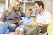 Happy Family Sitting on Sofa Watching Television