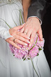 Bride and groom hands with wedding rings and bouquet
