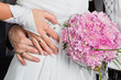 Bride and groom hands with wedding rings and bouquet