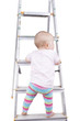 studio shot of a baby girl climbing up a ladder