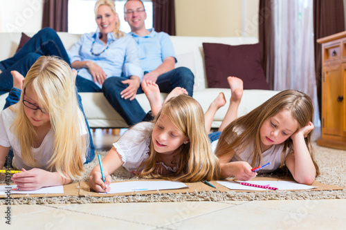 Photo: Family at home, the children coloring on floor Family at home, the children coloring on floor
