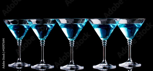 Photo: Blue cocktail in martini glasses isolated on black Blue cocktail in martini glasses isolated on black