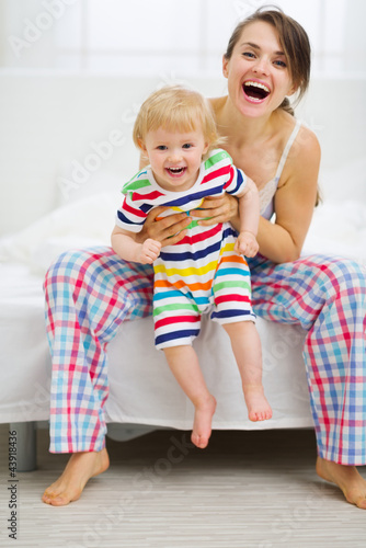 Photo: Portrait of happy young mother with baby in bedroom Portrait of happy young mother with baby in bedroom