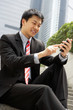 Chinese Businessman Dialling On Mobile Phone Outside Office