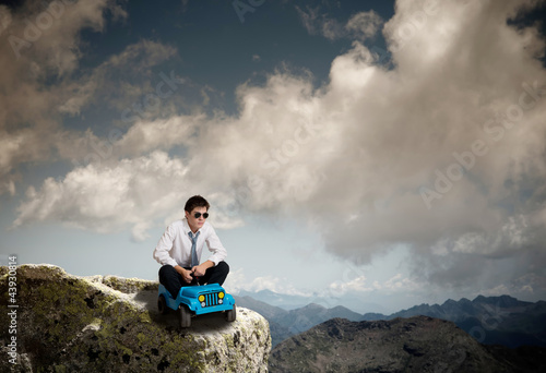Photo: concept of success - uomo con macchinina in vetta alla montagna concept of success - uomo con macchinina in vetta alla montagna