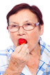 Senior woman eating strawberry
