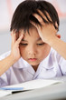 Unhappy Male Student Working At Desk In Chinese School Classroom