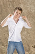 Young man in white shirt and blue jeans standing on the sand