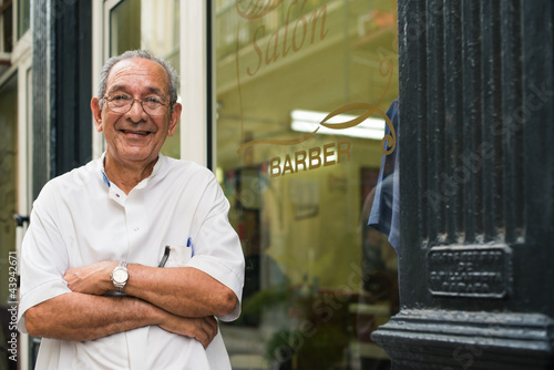 Photo: portrait of old barber smiling in hair salon portrait of old barber smiling in hair salon