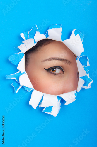 Photo: Female face through the hole in paper Female face through the hole in paper
