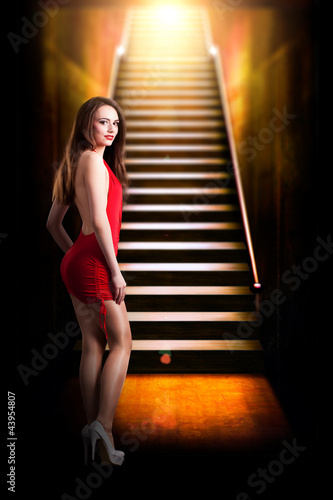 Photo: junge brünette im roten Minikleid am Fuße einer Treppe junge brünette im roten Minikleid am Fuße einer Treppe