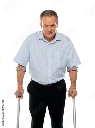Photo: Angry aged man with crutches looking at you Angry aged man with crutches looking at you