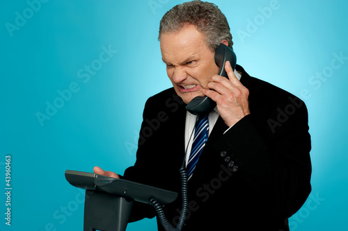 Photo: Irritated businessman communicating on phone Irritated businessman communicating on phone