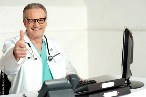 Photo: Smiling doctor gesturing thumbs up to camera Smiling doctor gesturing thumbs up to camera