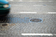 a car passing manhole cover on a paved road