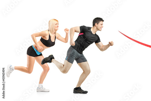 Foto: Male and female running towards finish line Male and female running towards finish line