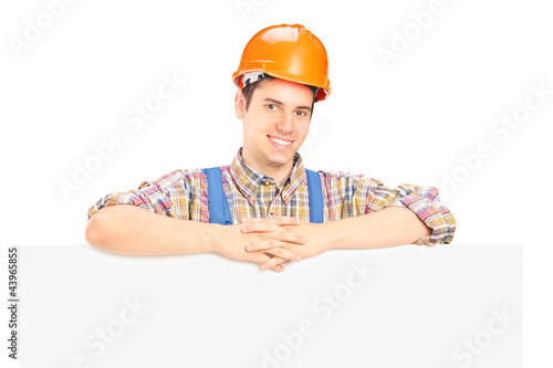 Photo: Satisfied male construction worker standing behind panel Satisfied male construction worker standing behind panel