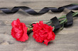 carnations and black ribbon on grey wooden background