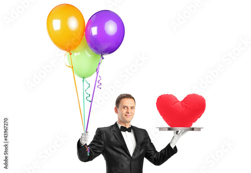 Foto: A butler holding balloons and a tray with a heart shape object A butler holding balloons and a tray with a heart shape object