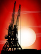 Silhouettes of two port cranes on a sunset