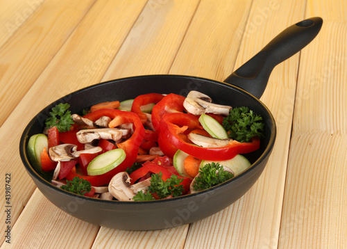 Photo: frying pan with vegetables on wooden background frying pan with vegetables on wooden background