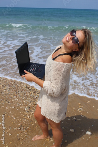 Photo: Beautiful blonde at the beach with laptop Beautiful blonde at the beach with laptop