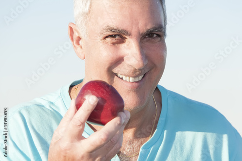 Photo: Mature man holding an apple Mature man holding an apple
