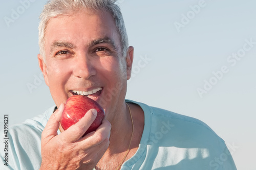 Photo: Mature man eating an apple Mature man eating an apple