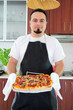 Foto: Young man in kitchen with homemade pizza Young man in kitchen with homemade pizza