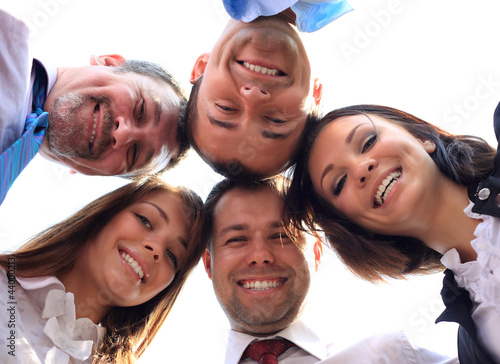 Photo: Low angle view of business people with their heads togethe Low angle view of business people with their heads togethe