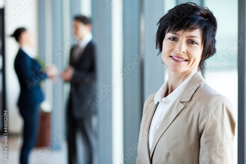 Foto: middle aged businesswoman in office with colleagues middle aged businesswoman in office with colleagues