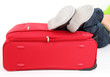 Legs of a young man lies on the red suitcase