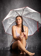 Frau sitzt mit Regenschirm im regen