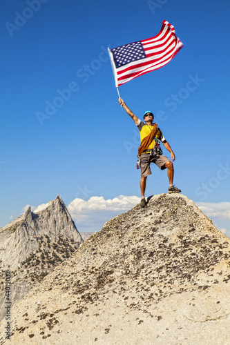 Photo: Climber waves flag on mountain peak. Climber waves flag on mountain peak.