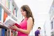 Pretty young college student in a library (shallow DOF; color to