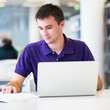 Handsome college student using his laptop computer in the campus