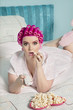 Portrait of shocked young woman watching television with popcorn while lying on bed