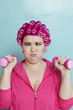 Photo: Young woman crossed eyes lifting dumbbell over colored background Young woman crossed eyes lifting dumbbell over colored background