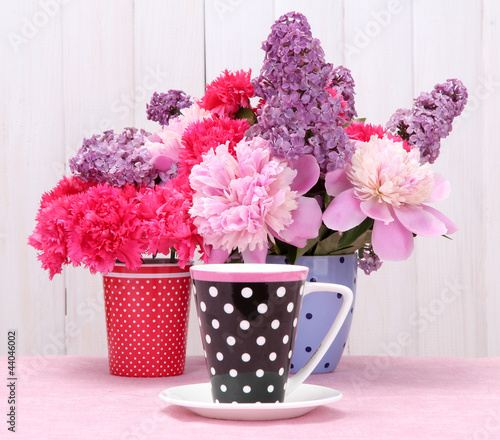 Photo: spring flowers and cup on table on white wooden background spring flowers and cup on table on white wooden background