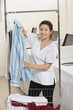 Photo: Portrait of a happy young woman hanging shirt in front of washing machines in Laundromat Portrait of a happy young woman hanging shirt in front of washing machines in Laundromat