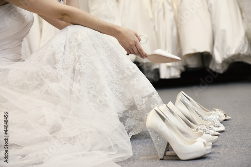 Photo: Low section of woman sitting with variety of footwear in bridal boutique Low section of woman sitting with variety of footwear in bridal boutique