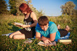 Photo: Two students read textbook against summer nature. Two students read textbook against summer nature.