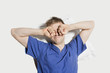 Young man rubbing eyes while waking up over colored background