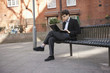 Young businessman using laptop while sitting on bench